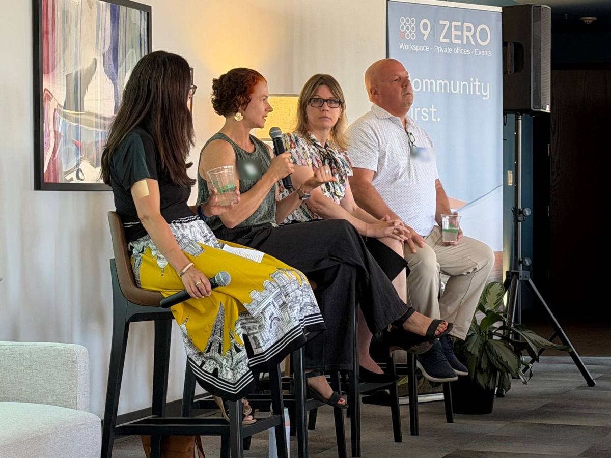 Four panelists speaking on stage at a community event.