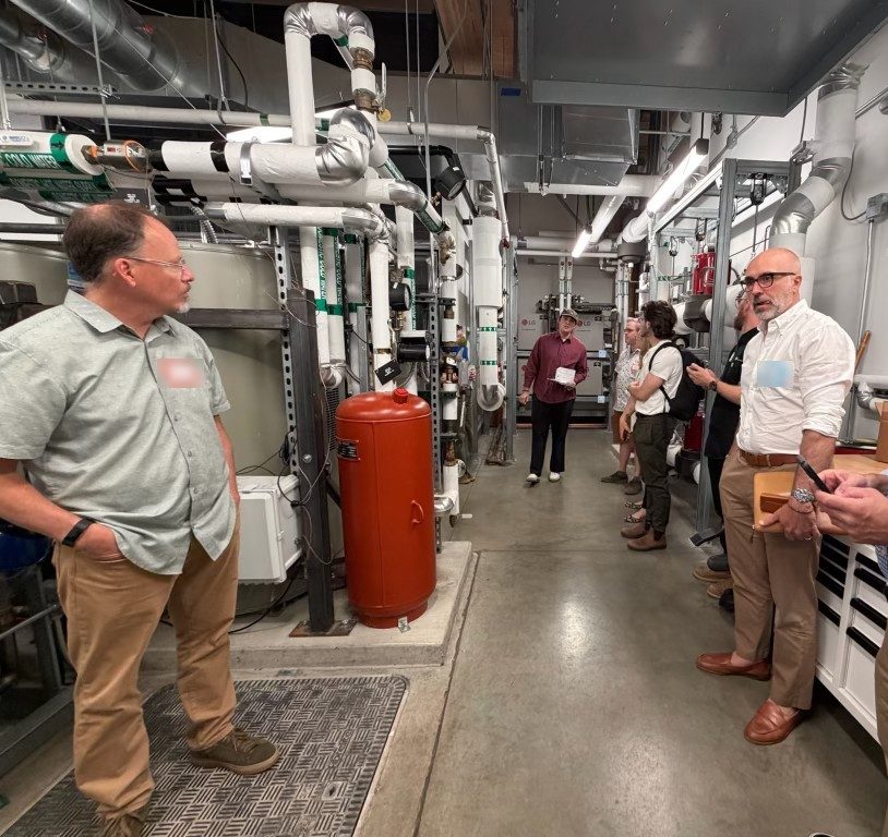 A group touring the mechanical room of an energy-efficient building.